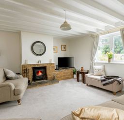 A living room with beige sofas a fireplace and a TV near a window at Holly Cottage Middle Tysoe in Tysoe