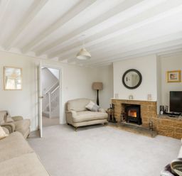 A living room with sofas a fireplace a television and a door showing a staircase at Holly Cottage Middle Tysoe in Tysoe