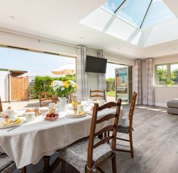 A dining area with a table set for breakfast near large open doors and a skylight at Mount View in Childswickham