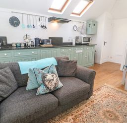 A kitchen area with green cabinets sofa and dining table at The Bath House in Blockley