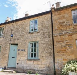 Stone cottage with three windows light blue door and plants outside at Red Fawn Cottage in Blockley