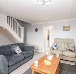 A living room with two sofas a wooden coffee table and stairs at Beach View House in Wyke Regis