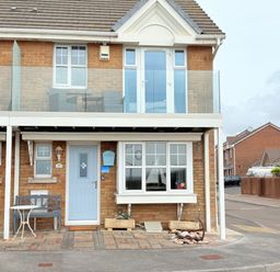 A brick house with a blue door a bench and a small table outside at Beach View House in Wyke Regis