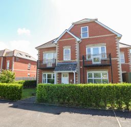 A red brick house with balconies and green hedges in front at Marina Reach Weymouth