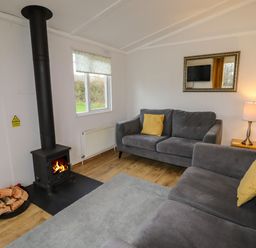 A living room with two gray sofas and a wood burning stove at Wayside Lodge in Aston On Clun
