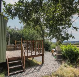 An outdoor area with wood deck, hot tub, and bench at Aston - Shepherd Hut Aston On Clun