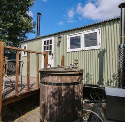 A shepherd hut with a wooden hot tub on a deck at Aston - Shepherd Hut Aston On Clun
