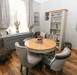 A dining room with round wooden table surrounded by grey chairs and a cabinet with shelves at 5 Pontardulais Road in Llangennech