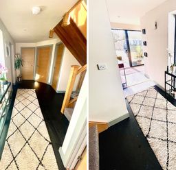 A hallway with a patterned rug a glass shelf holding potted plants wooden doors and stairs at Avalennek in St Newlyn East