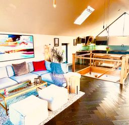 A living room with a sectional sofa and coffee table next to a kitchen area with a dining table at Avalennek in St Newlyn East