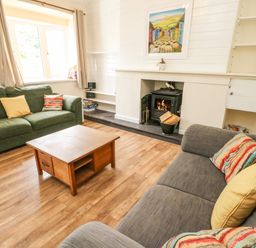 A living room with sofas a coffee table and a fireplace at Y Bwthyn Bach in Tregarth
