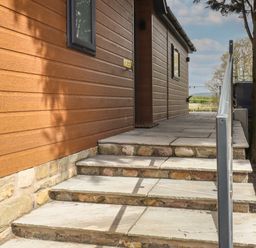 Stone steps with metal handrail leading to a wooden building with horizontal cladding at Ruperts Retreat in Nateby near Garstang