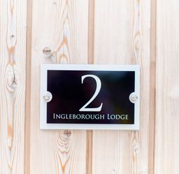 A black house number plaque with number 2 and Ingleborough Lodge text on wooden wall at Ingleborough Lodge in Rathmell near Settle
