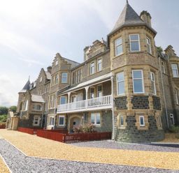 An exterior view of a large stone building with multiple windows and a balcony at On the Straits in Glyngarth near Menai Bridge