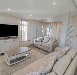 A living room with two sofas a coffee table a cabinet with a television and a large window at No 27 The Crab Pot in Runswick Bay near Staithes