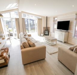 A living room with beige sofas a coffee table a TV on a cabinet and large windows at No 27 The Crab Pot in Runswick Bay near Staithes