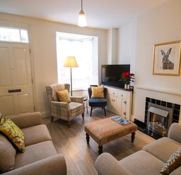 A living room with two sofas an armchair a blue chair and a coffee table at Primrose Cottage in Winchcombe