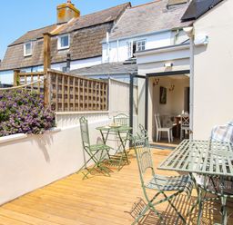 An outdoor patio area with green metal tables and chairs next to a white building at Blanche Cottage Brewers Quay Harbour