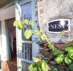 An entryway with a door and a sign at Nest Cottage in St Tudy