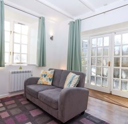 A snug with a sofa and curtains at Nest Cottage in St Tudy