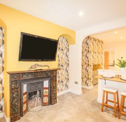A living room with a fireplace a wall mounted television and a breakfast bar with stools at Pams House in Weymouth