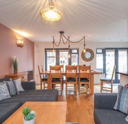 A living and dining area with sofas pillows dining table chairs and decorative lighting at Tolcarne in Porthtowan
