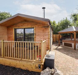 An outdoor patio with a wooden cabin and a covered hot tub at Celyn in Cyffylliog