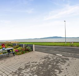 An outdoor area with a table and flowers overlooking the sea at Solway View in Skinburness near Silloth