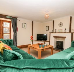A living room with green sofas a wooden coffee table a television and a fireplace at Wheal Prosper@The West Dry in St Austell