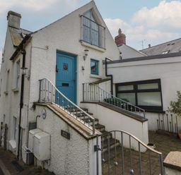An exterior view of a house with stairs and a blue door at Awen Ingli Newport, Pembrokeshire