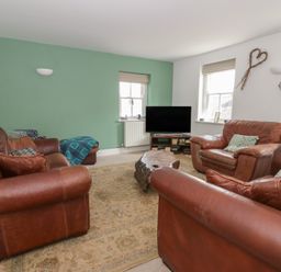 A living room with brown leather sofas and a television at Awen Ingli in Newport, Pembrokeshire