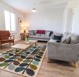 A living room with grey sofas a wooden coffee table and a floral rug at Ty Owen in Newport Pembrokeshire