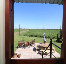 A view of a patio with chairs and a table from a doorway at Sweet Caroline Shepherd’s Hut Low Marnham near Sutton-On-Trent