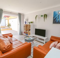 A living room with orange sofas a television on a stand and a bookshelf at Mermaid House in Brewers Quay Harbour
