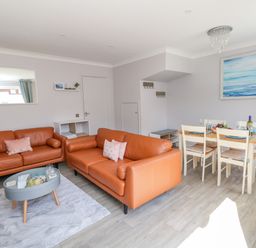 A living room with two orange sofas a dining table with four chairs and a blue artwork on the wall at Mermaid House in Brewers Quay Harbour