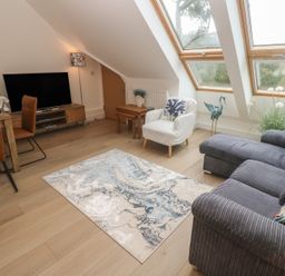 A living room with a television, sofa, and dining table at Upper Deck in Truro