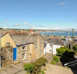 A coastal village with stone houses and a view of fishing boats in the harbor at Walter in Newlyn