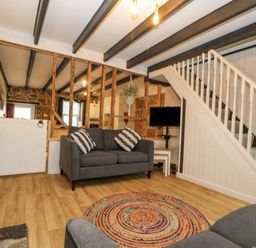 A living room with gray sofas and a colorful round rug near a staircase at Walter in Newlyn