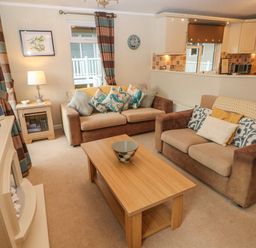 A living room with two sofas a wooden coffee table and a fireplace at 16 Heritage Park in Heritage Park near Kilgetty