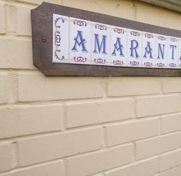 A decorative tile sign with the word Amaranta mounted on a beige brick wall at Amaranta Brewers Quay Harbour