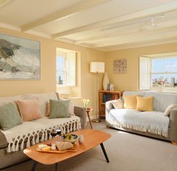 A living room with two sofas and a wooden coffee table with food and wine at Faraway Cottage in St Levan near Porthgwarra