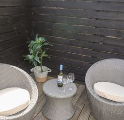 A corner patio with two round wicker chairs and a small wicker table with a bottle and two glasses at Dolwyn in Llandegfan