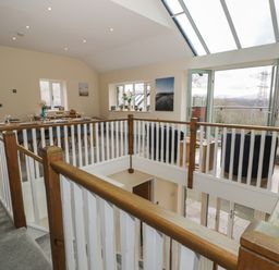 An open dining and sitting area with a wooden railing and large skylight at Tan Twr in Llanfairpwll
