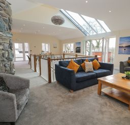 A living room with sofas a coffee table and a stone wall next to large skylights at Tan Twr in Llanfairpwll