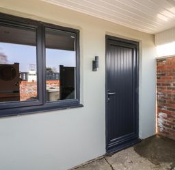 An entrance area with a dark door numbered 1 and a window next to it with brick walls at Chalet 5 in Sherburn