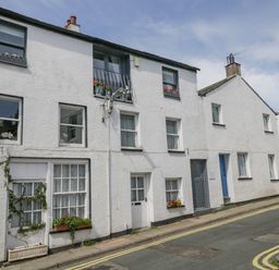 A street with white terraced houses and flower boxes on windows at The Old Mill in Keswick