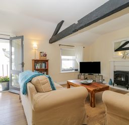 A living room with beige sofas wooden coffee table tv and bookshelf at The Old Mill in Keswick