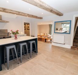 A kitchen with an island and stools and a dining area in the background at Ley Mill Farm in Huntley