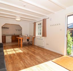 A living room with a kitchen area and seating at Bracken Cottage St Tudy