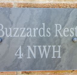 A stone wall with a grey plaque engraved with Buzzards Rest and 4 NWH at Buzzards Rest in Stannington near Morpeth